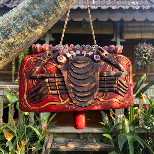 Lonceng Sapi Cowbell by TIBA-TIBA –
Carved Mahogany cowbell with red crab tropical design hanging from a frangipani tree in front of a Balinese Joglo