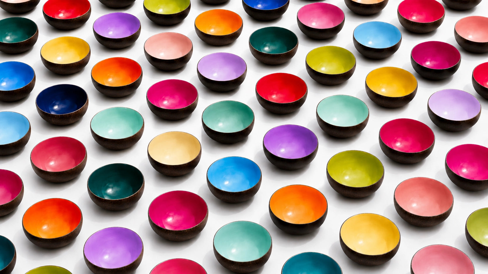 A large collection of DOTS colourful coconut bowls by TIBA-TIBA in an alternating grid of tropical colours filling the frame on a white background. 