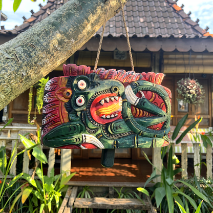 Lonceng Sapi Cowbell by TIBA-TIBA – 
Balinese solid carved Mahogany cowbell with dark green dragon design hanging from a frangipani tree in front of a Joglo 