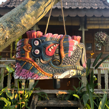 Lonceng Sapi Cowbell by TIBA-TIBA – 
Bali made solid Mahogany carved cowbell with dark green Garuda design hanging from a frangipani tree in front of a Joglo 