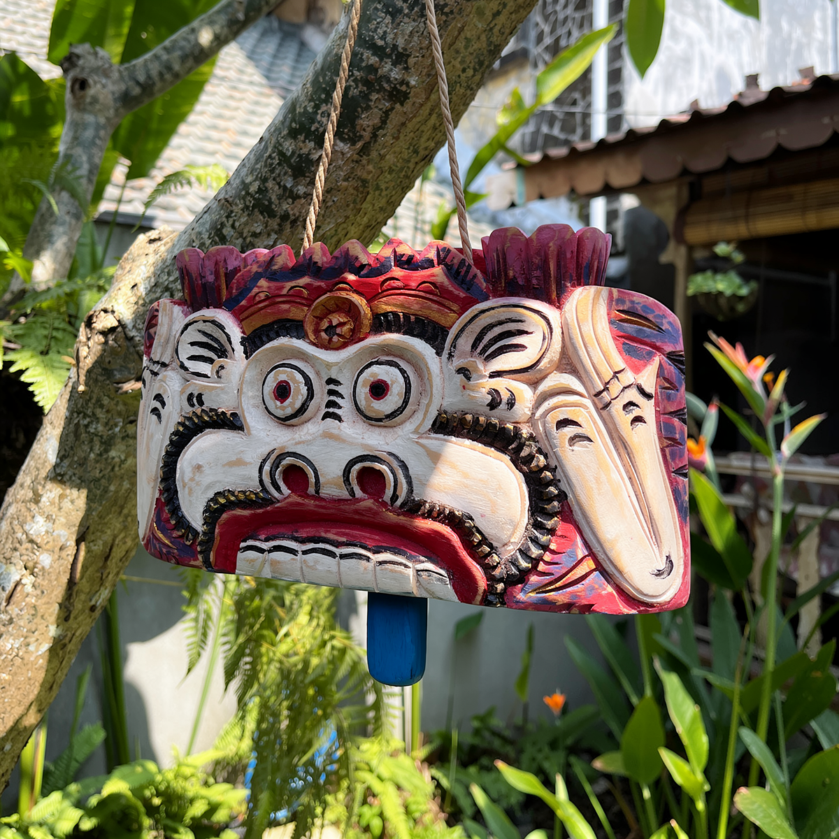 Lonceng Sapi Cowbell by TIBA-TIBA – 
Solid carved Mahogany cowbell with monkey design hanging from a frangipani tree in front of a Joglo 