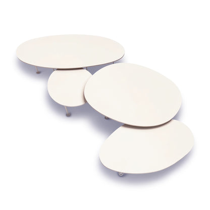 A set of four nested, organic-shaped Pebbles - Coffee Tables by TIBA-TIBA in a warm off-white finish of Dekton Aeris, resting on a white studio background. 