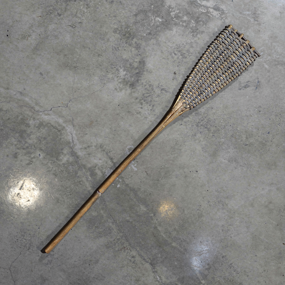 Rattan Fly Swatter by TIBA-TIBA – natural rattan fly swatter made by the Kalimantan Utik river tribe Iban Dayak on grey concrete background.