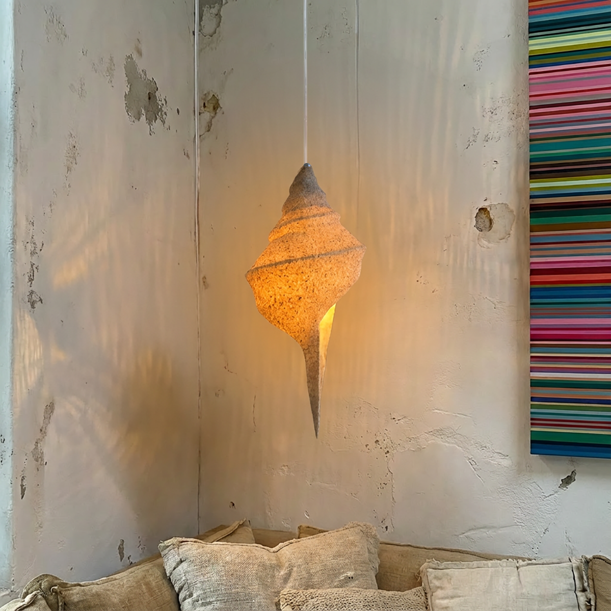 Keong Pendant Light by TIBA-TIBA - sand coated resin conch shell pendant lamp hanging in a loft with a Gerhard Richter Strips painting in background. 
