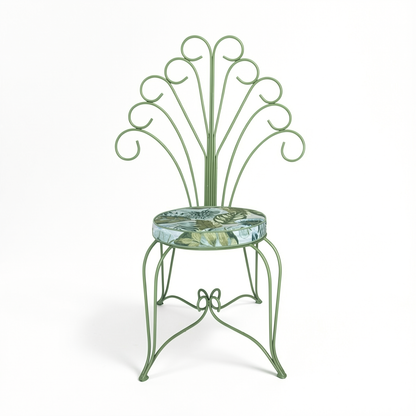 Plume Chair by TIBA-TIBA – powder-coated sage green steel peacock chair with curled metal frame and sage green tropical foliage outdoor cushion, front view. 