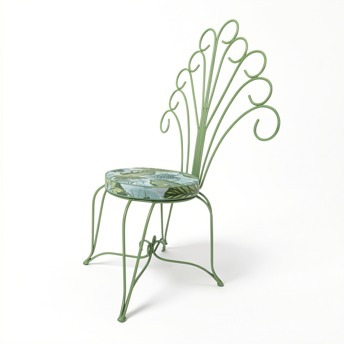 Plume Chair by TIBA-TIBA – powder-coated sage green steel outdoor peacock chair with curled frame and jungle print patterned cushion.