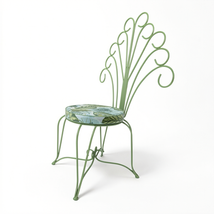 Plume Chair by TIBA-TIBA – powder-coated sage green steel outdoor peacock chair with curled frame and jungle print patterned cushion.
