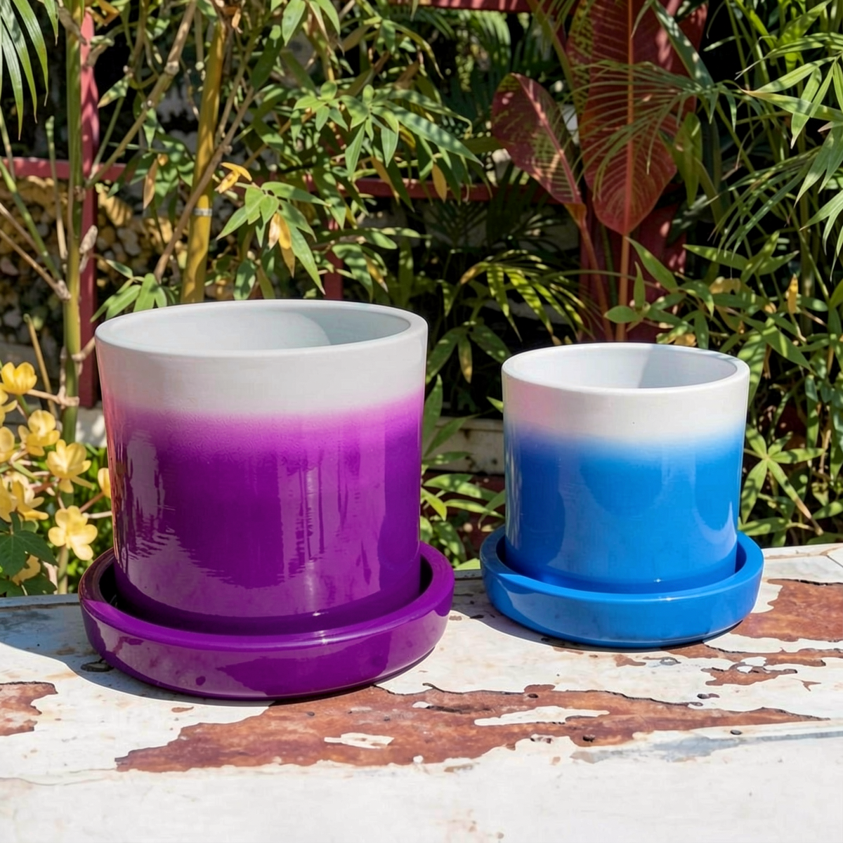 Fade Planter and Tatakan Plant Saucer by TIBA-TIBA - Two gradient-colored planters, one purple to white and the other blue to white, on a wooden surface with a garden background.
