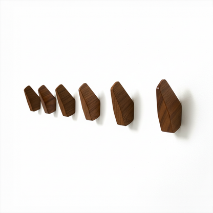 Fin Wall Hook by TIBA-TIBA -  Row of six sculptural, abstract teak wall hooks mounted on a white wall. 