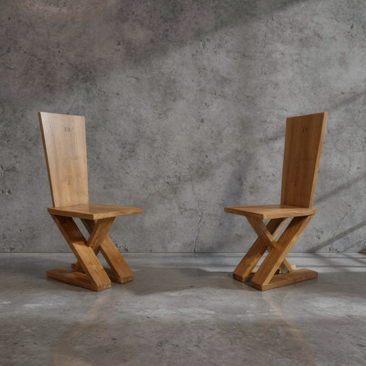 Zag-Zig Chair by TIBA-TIBA – Two chunky, brutalist teak wood chairs cut from a single plank of wood on concrete background.   