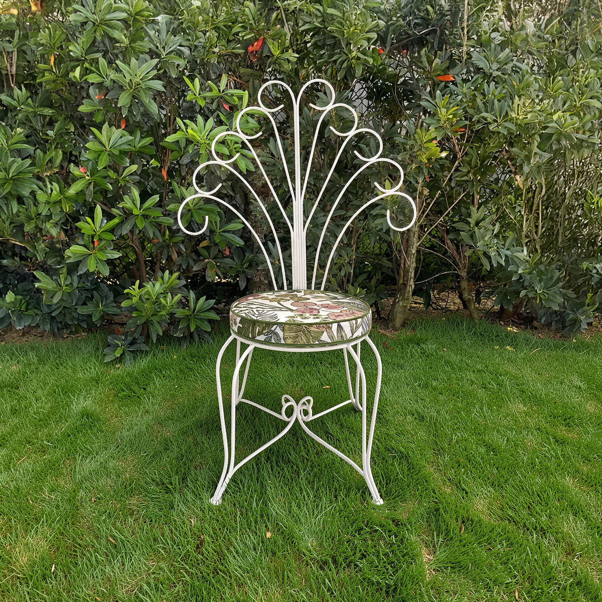 Plume Chair by TIBA-TIBA – powder-coated white metal peacock chair with curved steel back in garden setting.