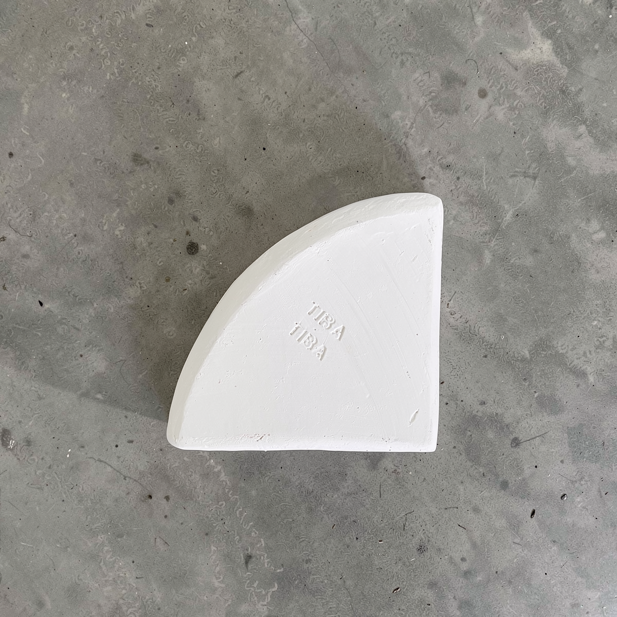Po-Ka Pot feet by TIBA-TIBA - detail of a white glazed ceramic pot foot wedge to lift pots for drainage and to prevent root rot on concrete background. 